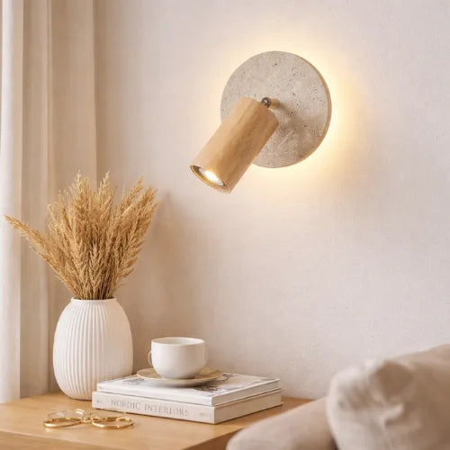 Applique murale Aksel en travertin et bois clair, éclairage directionnel installé au-dessus d’une table d’appoint dans un intérieur au style scandinave épuré.