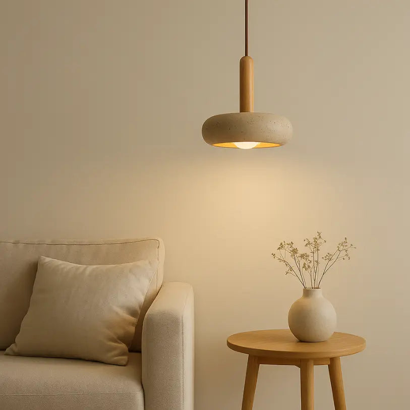Suspension en travertin naturel Elys éclairant un salon moderne avec lumière douce, au-dessus d’un canapé beige et d’une table en bois.