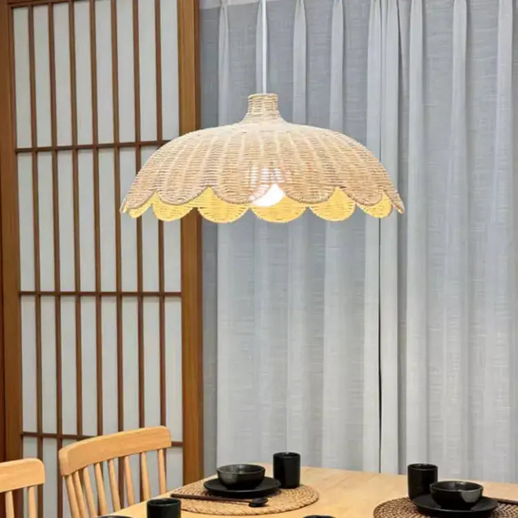 Suspension en rotin naturel HEDDA diffusant une lumière douce au dessus d'une table à manger dans un intérieur au style nordique. 