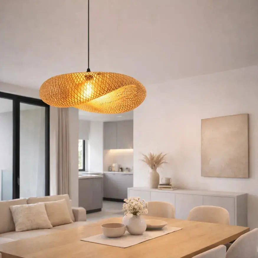 Suspension Aina en rotin tressé au design scandinave au-dessus d’une table en bois clair dans une salle à manger minimaliste