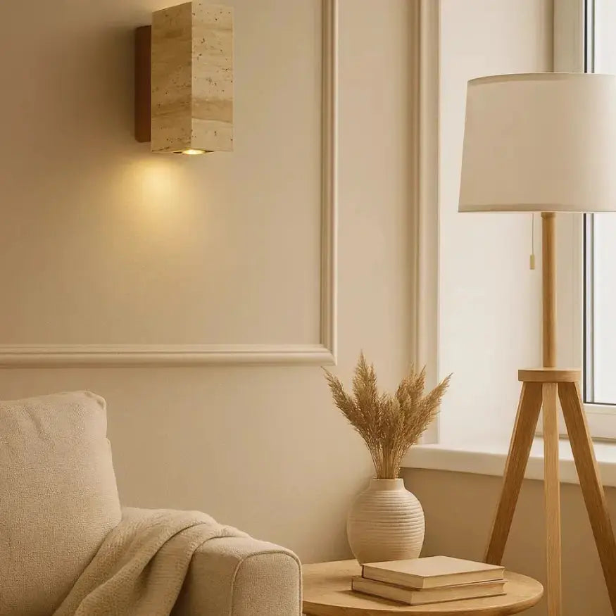 Applique murale en travertin ELIN éclairant un salon au style scandinave, lumière douce, déco naturelle beige et bois.