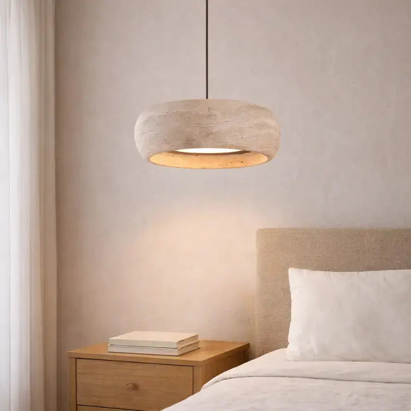 Suspension Isla en travertin diffusant une lumière douce dans une chambre minimaliste et épurée 